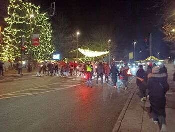 Športniki in športnice z baklami in lučkami skozi mesto