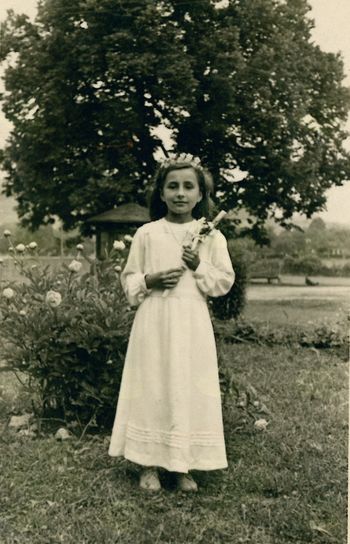 Silva Lebič pri sv. obhajilu leta 1956, slikana ob rožah v parku nasproti starega župnišča, v ozadju je vrtna uta (arhiv družine Korošec).