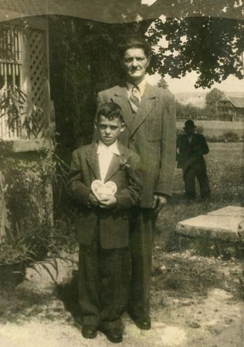 Franci Korošec pri sv. birmi z botrom leta 1952 ob vrtni uti pod lipo, v ozadju je Pavšerjev kozolec (arhiv družine Korošec).